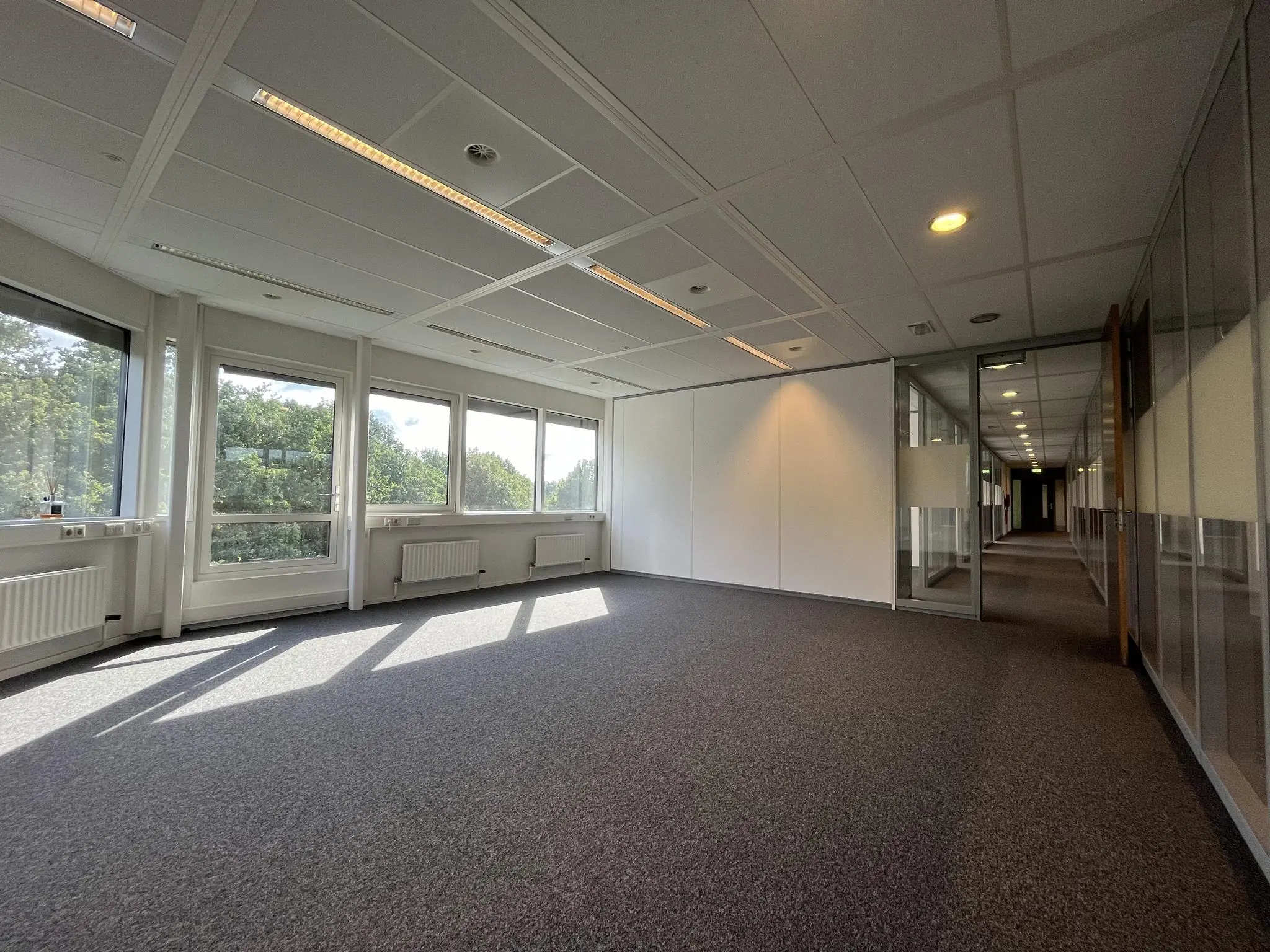 Lichte, lege kantoorruimte aan de Baarnsche Dijk met grote ramen en uitzicht op groen.